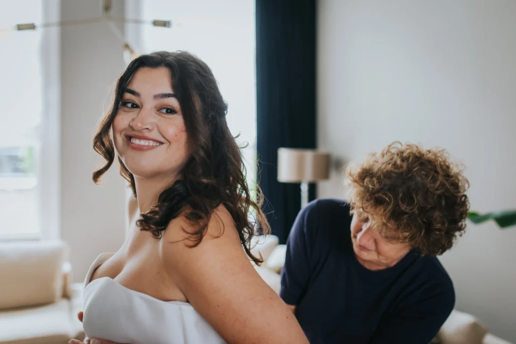 Bride smiling while dress is being adjusted