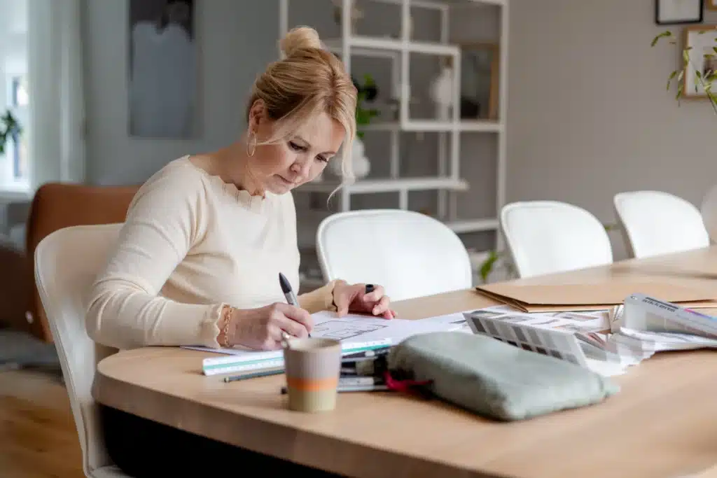Woman sketching design plans at dining table