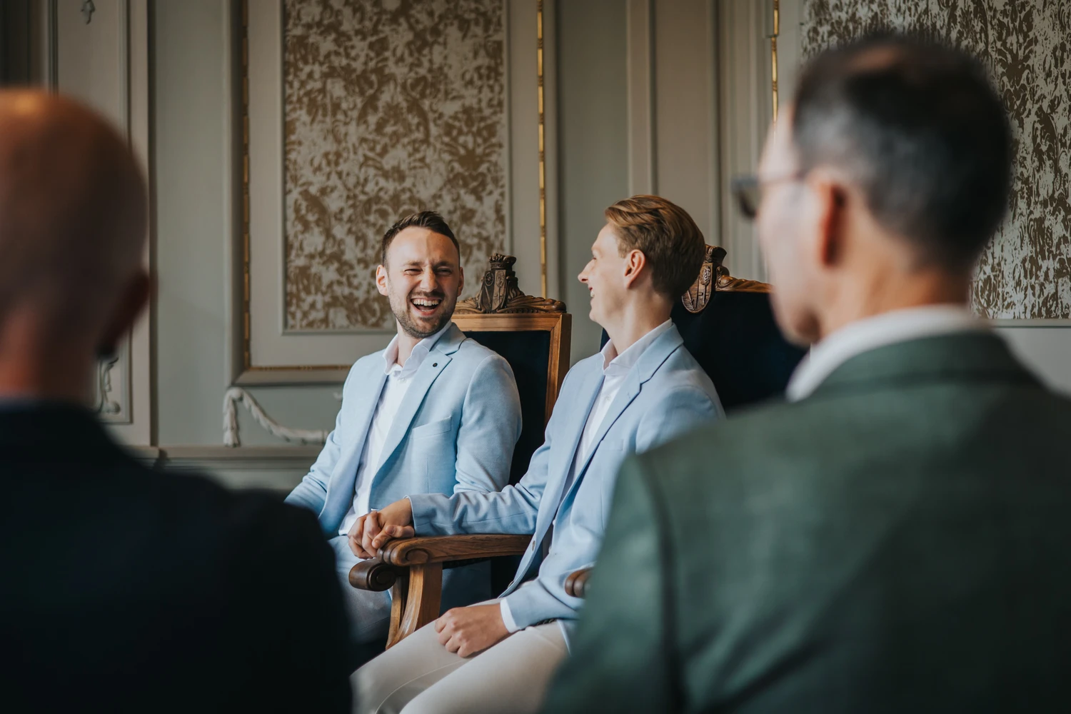 Bedrijfsfotografie: vier mannen in casual zakelijke kleding hebben een gesprek in een elegant interieur met klassieke wandbekleding in Friesland.